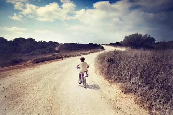 Junge reist allein mit dem Fahrrad durch eine trostlose Landschaft — Stockfoto