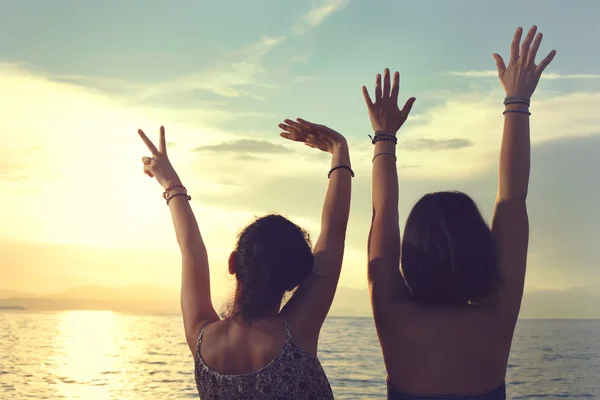 Mujeres jóvenes abrieron sus manos al atardecer en el mar de vacaciones —  Fotos de Stock