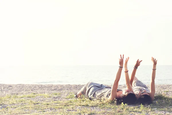 Junge Frauen, die auf der Wiese liegen, heben zum Zeichen der Freundschaft die Arme — Stockfoto