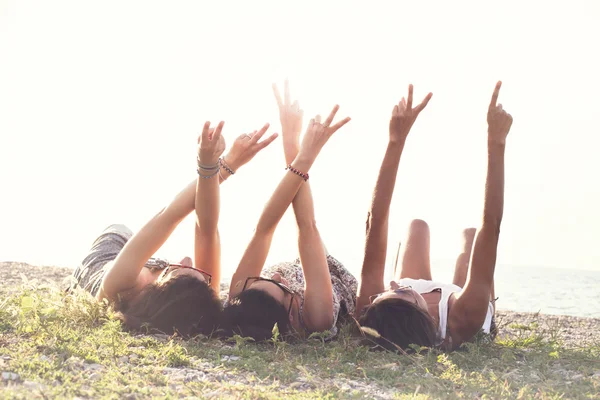 Mladé ženy leží na louce zvýšit své ruce na znamení přátelství — Stock fotografie