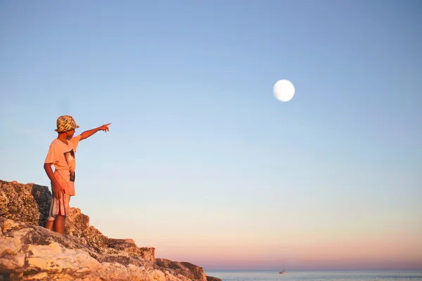 Dreamy boy points his finger with the moon in the sky — Stock Photo, Image