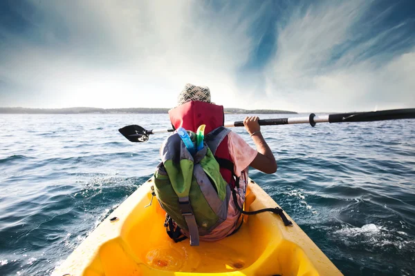 Ung pojke plogar genom vattnen i havet med sin kanot — Stockfoto