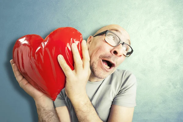 Uomo innamorato tiene un cuscino rosso a forma di cuore — Foto Stock