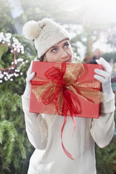 Femme rêveuse, tenant son cadeau de Noël — Photo