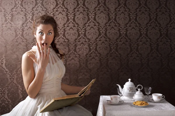 Verrast vrouw lezen van een boek op theetijd — Stockfoto