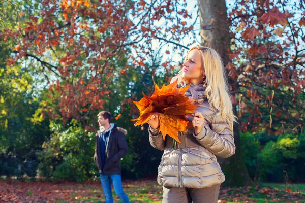 Mulher está segurando as folhas no outono — Fotografia de Stock