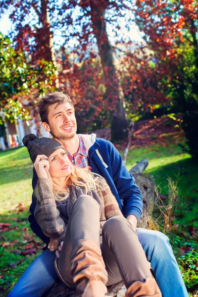 Pareja sentada en un tronco de árbol en un parque —  Fotos de Stock