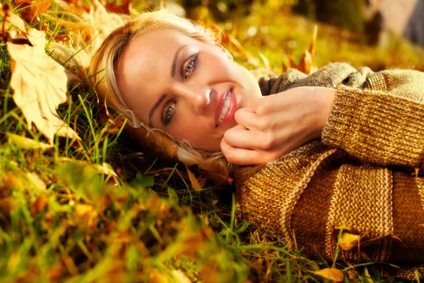 Beautiful woman lying down on autumn leaves — Stock Photo, Image