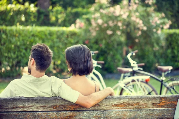 Casal apaixonado abraçando cada um em um banco com bicicletas — Fotografia de Stock