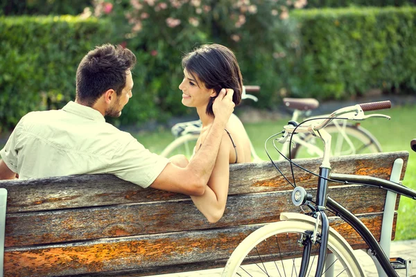 Casal apaixonado acariciando-se em um banco com bicicletas em vacatio — Fotografia de Stock