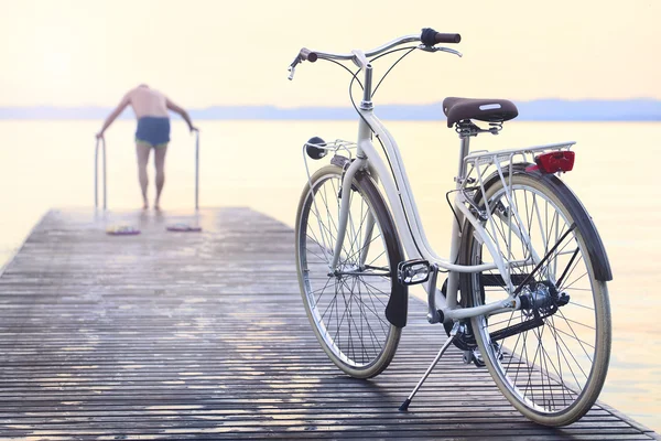 Человек паркует велосипед на набережной перед прыжком в воду — стоковое фото