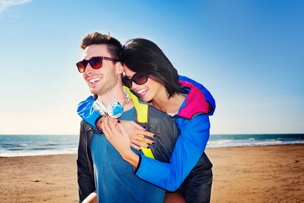 Mann trägt ihren Partner am Strand auf dem Rücken — Stockfoto