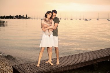 Couple flirting on the boardwalk at the lake clipart