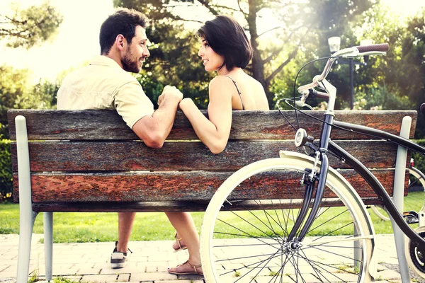 Casal apaixonado sentados juntos em um banco com bicicletas — Fotografia de Stock