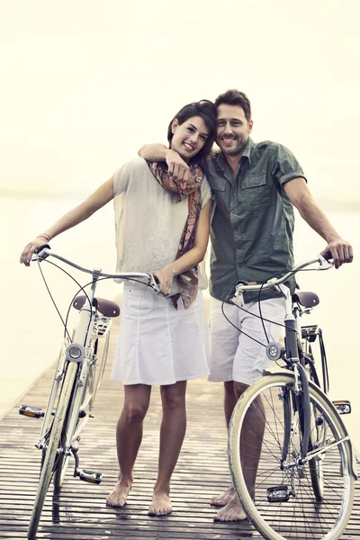 Pareja en el amor empujando su bicicleta toghether en un paseo marítimo — Foto de Stock