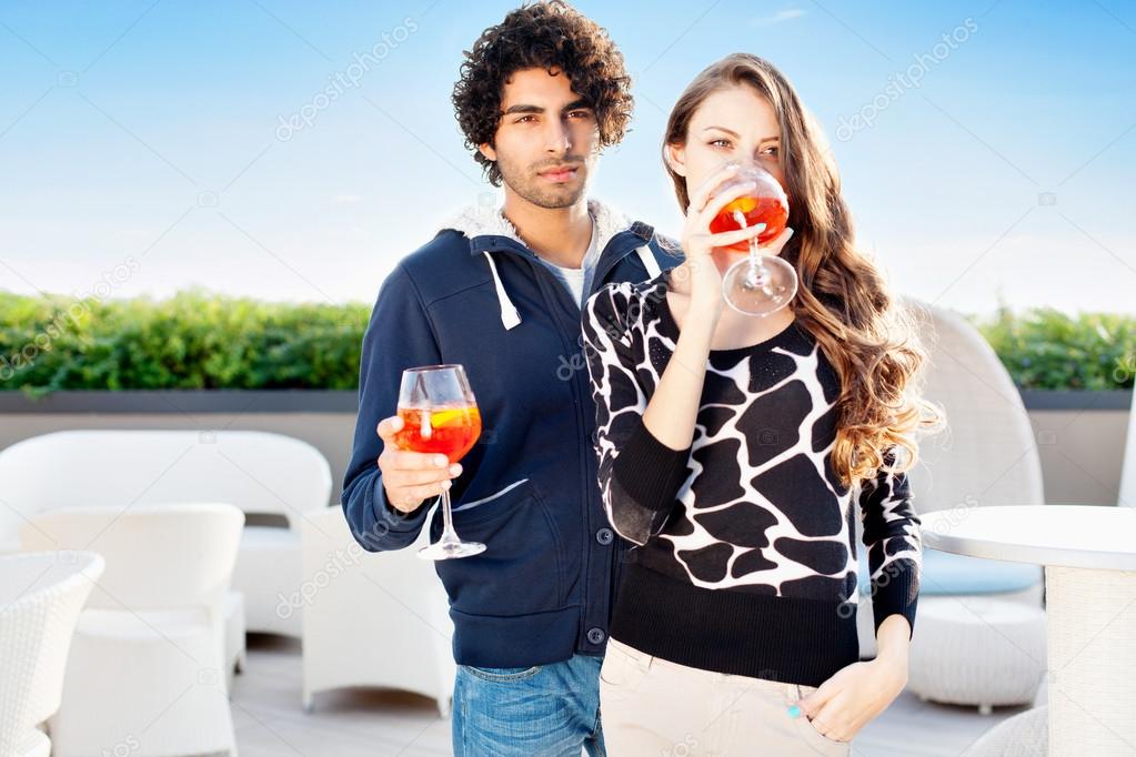 Young couple standing drinking cocktails