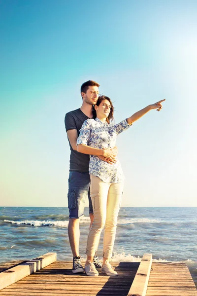 Szczęśliwa młoda para stojący wskazując w niebo — Zdjęcie stockowe