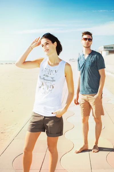 Jeune couple de touristes debout sur une promenade de plage — Photo