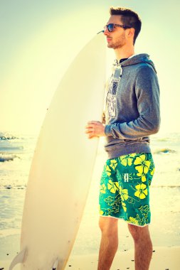 pensive surfer  waiting for the perfect wave on the beach clipart