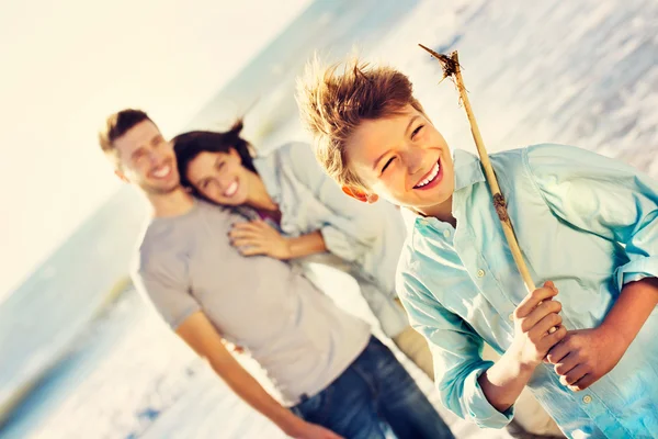 Wild boy posing for a photo at the sea while parents look at him — Stock Photo, Image