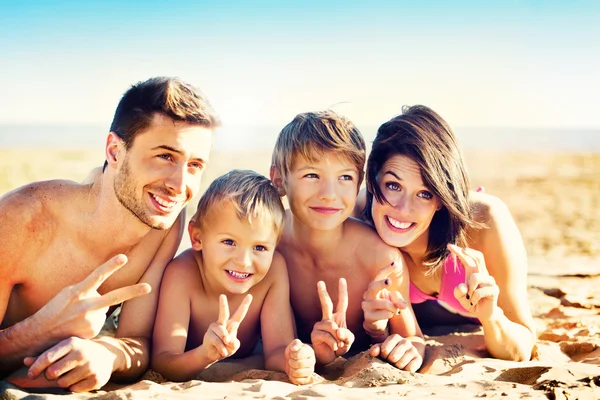 Lycklig familj poserar för ett souvenir foto på stranden framför t Stockbild