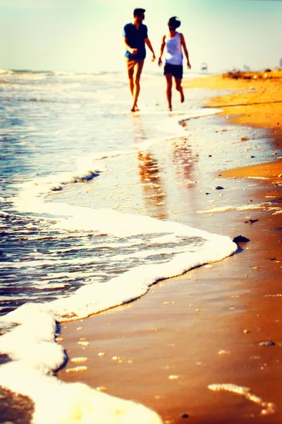 Ευτυχισμένο ζευγάρι παίζοντας στην παραλία και στο ηλιοβασίλεμα — Φωτογραφία Αρχείου