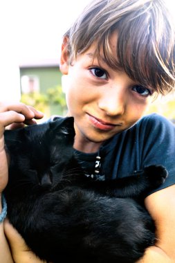 Çocuk sevgi ile siyah kedi onun gösterir.