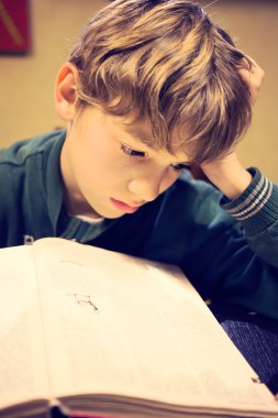 Genç bir çocuk üzerinde ödev konsantre.