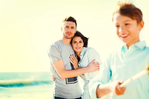 Ouders kijken haar zoon terwijl ze speelt op de zee strand — Stockfoto