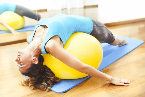 Mujer haciendo ejercicios corporales sobre una bola amarilla — Foto de Stock