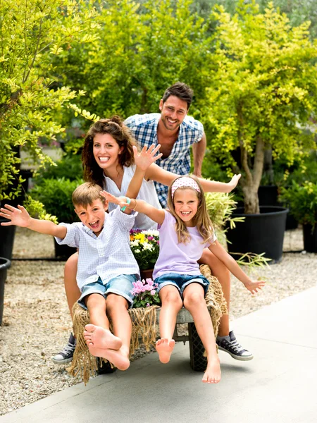 Familia divirtiéndose con una carretilla en un invernadero — Foto de Stock
