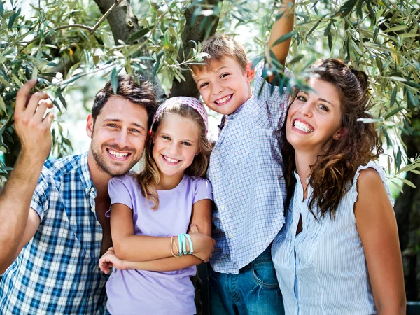 Família se divertindo sob uma árvore de olivesin uma estufa — Fotografia de Stock