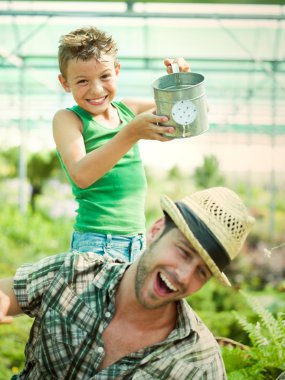 Happy Young boy playing with his father in a green house clipart