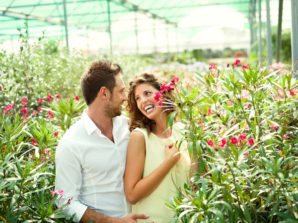 Casal se divertir escolhendo vasos de flores em uma estufa — Fotografia de Stock