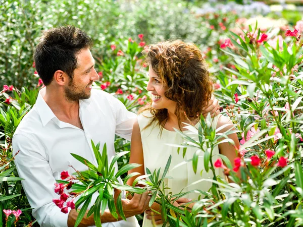 Couple flirting among the flowers in a greenhouse — Stock Photo, Image
