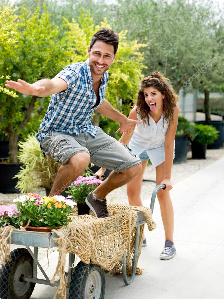 Young couple playing with a wheelbarrow in a greenhouse