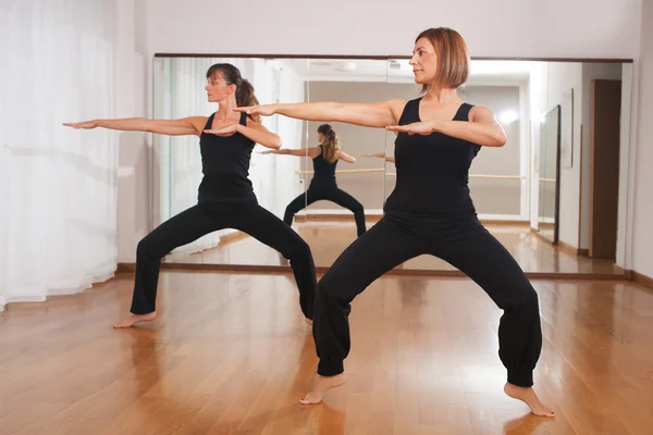 Dos mujeres haciendo un ejercicio de fitness en sincronía — Foto de Stock