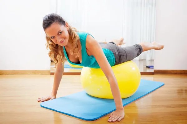 Femme faisant des exercices de corps sur une balle jaune — Photo