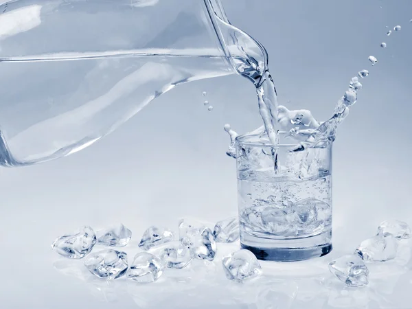 Cubitos de hielo cayendo en un vaso de agua — Foto de Stock