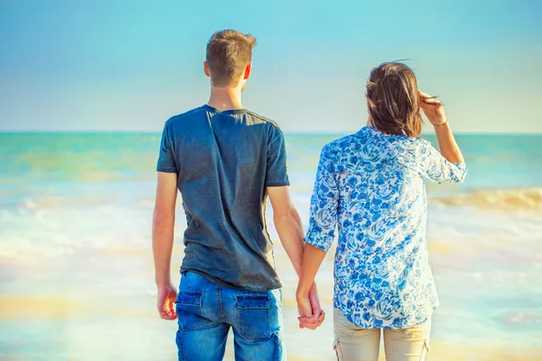 Casal jovem andando na praia enquanto segurando as mãos — Fotografia de Stock