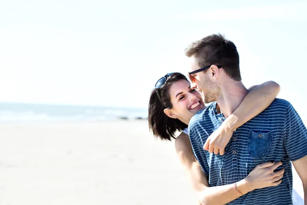 Pareja enamorada abrazándose cariñosamente frente al mar — Foto de Stock