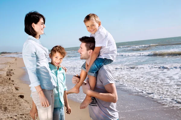 Happy family posing for a souvenir photo on the beach front of the sea — Stock Photo, Image