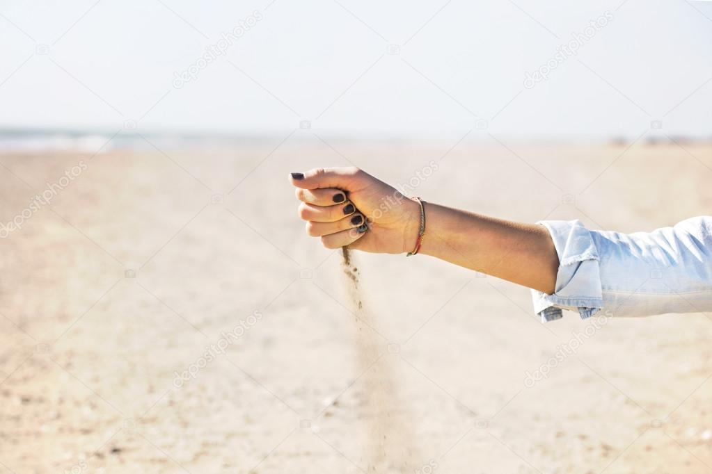 Woman with sand falling through her hands on the beach