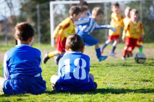 サッカーをしながら彼らのチームを見ている制服を着た若い男の子 — ストック写真