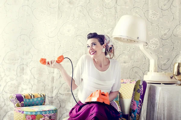 Vintage hemmafru chattar på telefonen i frisersalong Stockbild
