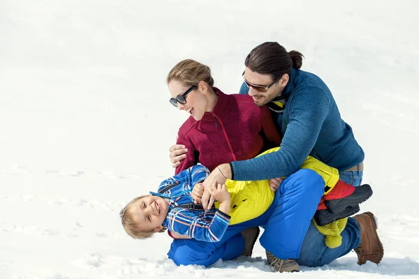 Familie verwennerij van hun zoon in de sneeuw — Stockfoto