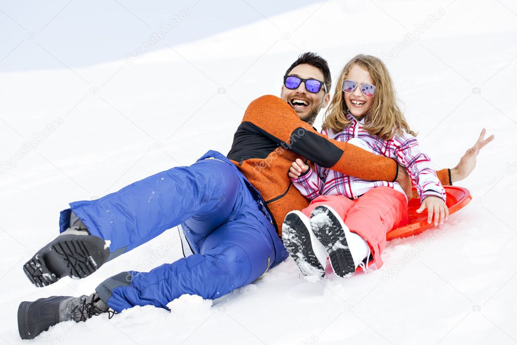 Girl and his father sledding very fast in montain