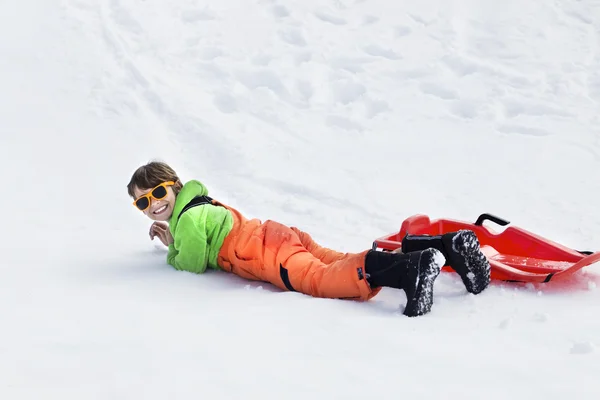 Kleine jongen rodelen zeer snel en valt in de sneeuw — Stockfoto