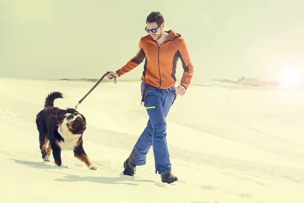 Чоловік і його собака біжать снігом — стокове фото