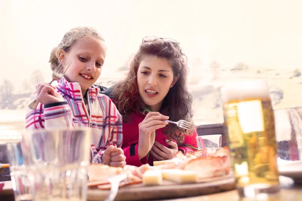 Mom and daughter have lunch in a chalet in the mountain — Stock Photo, Image